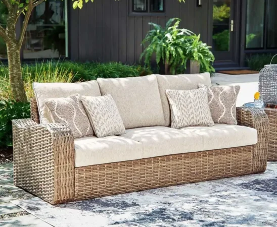 Outdoor wicker sofa with beige cushions and pillows.